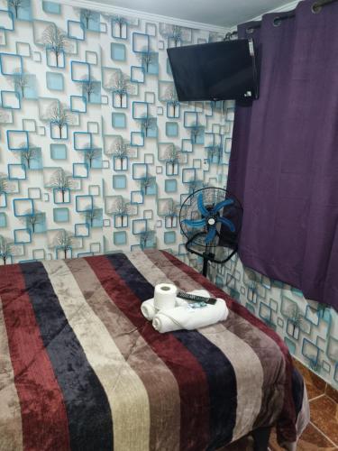a bedroom with a bed with a blanket and a fan at Hotel Simon in Antofagasta
