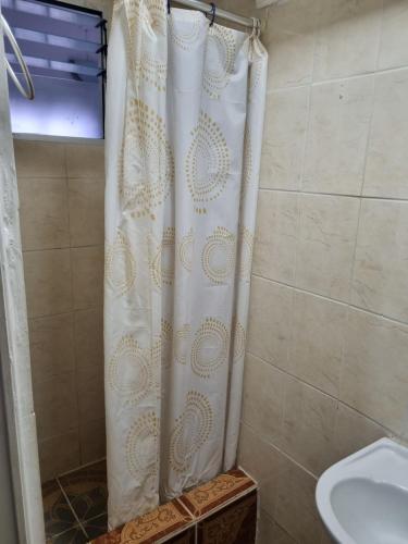 a shower with a white shower curtain in a bathroom at Hotel Simon in Antofagasta