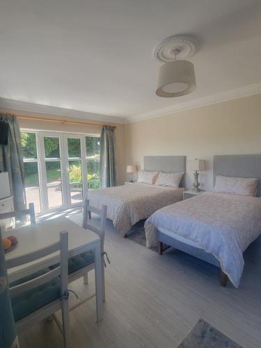 a bedroom with two beds and a table and a window at Spring Grove Guesthouse in Donegal
