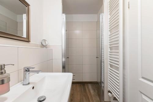a white bathroom with a sink and a shower at Haevn Erholung, Feuer, Wasser, Luft in Reußenköge