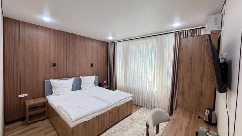 a small bedroom with a bed and a television at Turon plaza hotel in Bukhara
