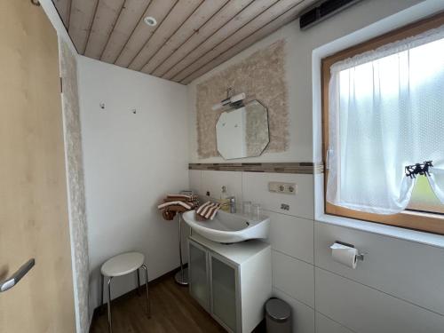a white bathroom with a sink and a window at Ferienwohnung 1 Am Krepbach in Grainau