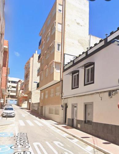 an empty city street with a car parked on the street at Playa a dos pasos in Santa Pola
