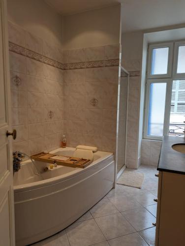 a white bathroom with a tub and a window at Maison familiale en centre bourg in Ahun