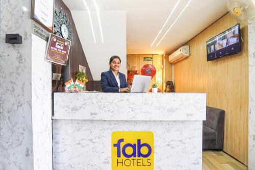 a woman standing behind a counter with a laptop at FabHotel The Max in Lucknow