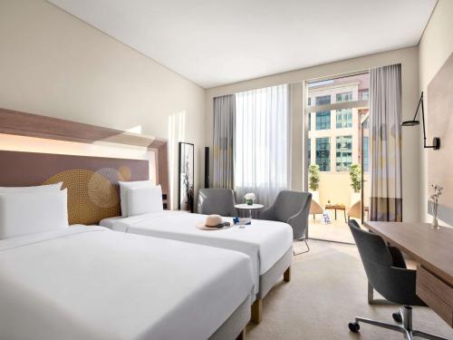 a hotel room with two beds and a desk at Novotel Bur Dubai - Healthcare City in Dubai