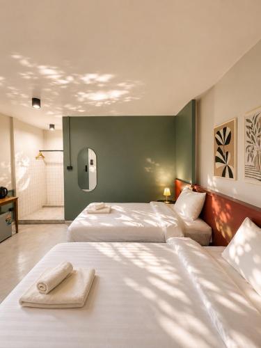 a bedroom with two beds and a green wall at Quicky Stay Hotel Suphanburi in Suphan Buri