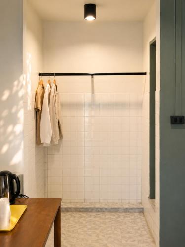 a bathroom with a shower with white tiles at Quicky Stay Hotel Suphanburi in Suphan Buri