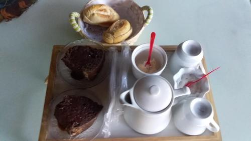 ein Tablett mit Kuchen und Tassen auf einem Tisch in der Unterkunft Caveira in Mairiporã