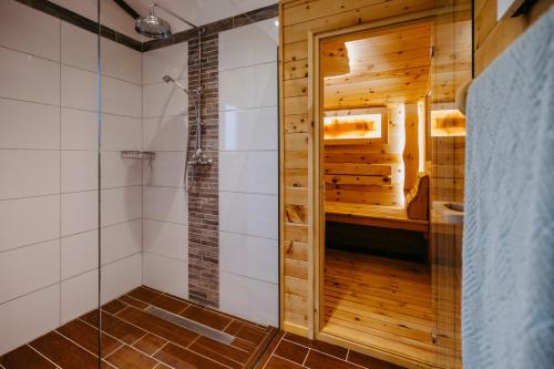 a bathroom with a shower with a wooden wall at Ferienhaus Weiss in Oberschützen