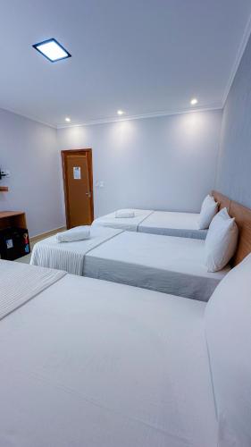 a hotel room with three beds with white sheets at Hotel e Restaurante Os Sertões in Canudos
