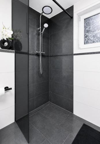 a bathroom with a shower with black tiles at Ferienhaus Schieferland in Müllenbach