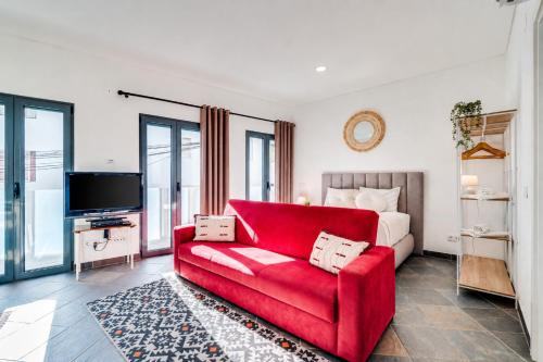 a living room with a red couch and a bed at Studio - Old Town Albufeira in Albufeira