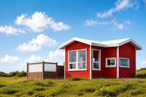 a red house in a field of grass at Blue View Cabins in Reykholt