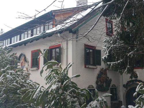 a white building with red shuttered windows in the snow at Haus Wartenberg in Salzburg