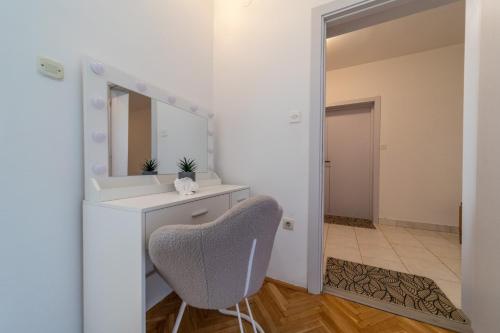 a bathroom with a mirror and a chair at Rooms and Apartments Lidija in Lopar