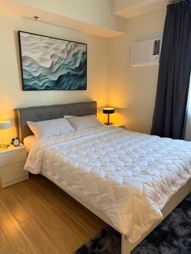 a bedroom with a bed with a painting on the wall at Maison Angela Suites in Biñan
