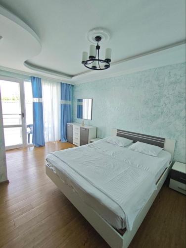 a bedroom with a large white bed with blue walls at Luka & Eka in Kobuleti