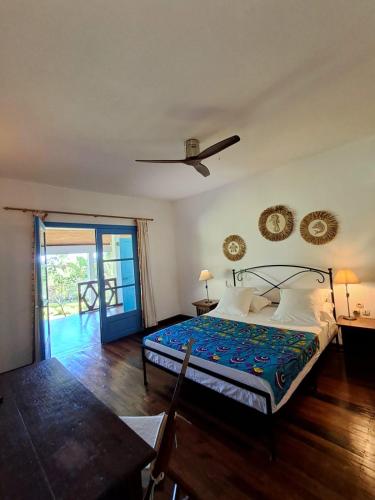 a bedroom with a bed and a table and a door at Villa Orita in Nosy Be