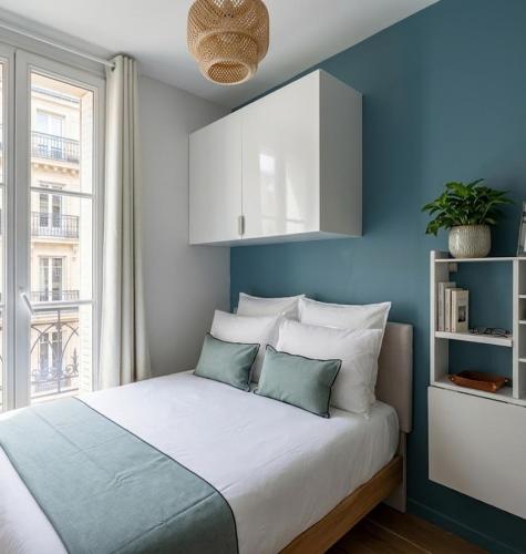 a bedroom with a bed with blue walls and a window at Hôtel My Suite Paris in Paris
