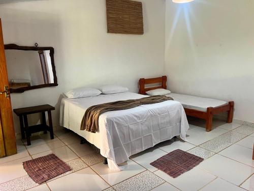 a bedroom with a bed and a chair and a mirror at Pousada Recanto Guará Oficial in Pirenópolis