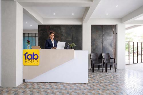 a woman standing at a reception desk with a laptop at FabHotel Infinity Residency in Pune