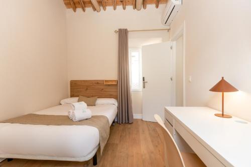 two beds in a room with white walls and wooden floors at Hospedería Boho Granada by eme hoteles in La Zubia