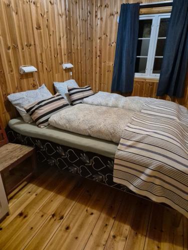 a bed in a room with wooden floors and a window at Sjøhaug Rorbu, Fishcermanns cabin in Moskenes