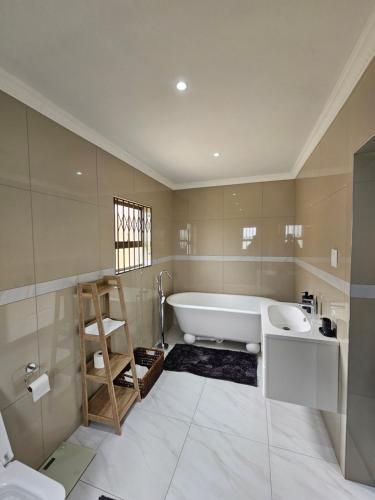 a bathroom with a bath tub and a sink at Posimuma in Centurion