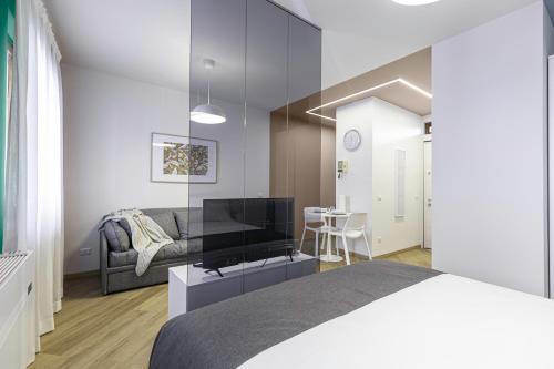a bedroom with a bed and a tv and a couch at Il Chiostro di Santa Caterina in Vimercate