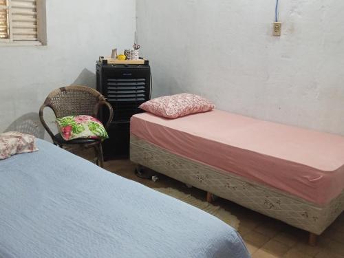 a bedroom with two beds and a chair and a table at Pousada Mais E Vida 24h in Teresina