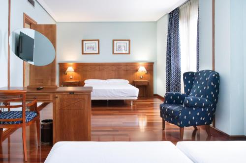 a bedroom with a bed and a desk and a chair at Checkin Basic León Norte in León