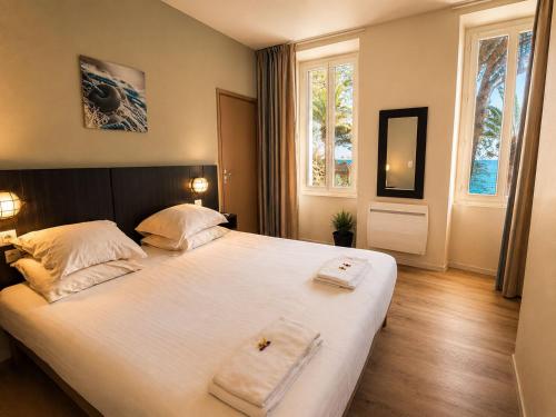 a bedroom with a large bed with two towels on it at Hotel VTF Clairefont - Bandol in Bandol