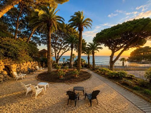 a park with chairs and palm trees and the ocean at Hotel VTF Clairefont - Bandol in Bandol
