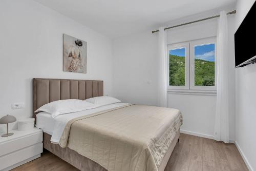 a white bedroom with a large bed and a window at Villa Magdalena in Zavojane