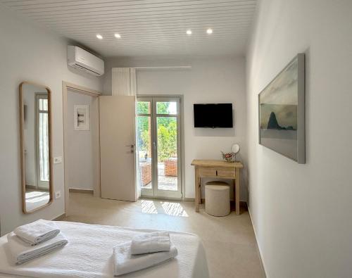 ein weißes Zimmer mit einem Bett und einem Fernseher in der Unterkunft Villa Anthousa luxury villas and suites in Anthoúsa