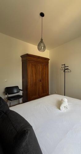 a bedroom with a large white bed with a wooden cabinet at La suite du parc 2 in Nancy