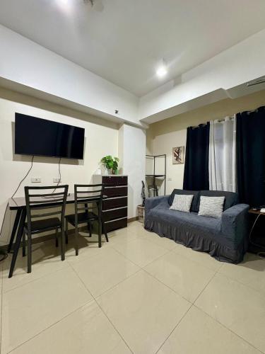 a living room with a bed and a table and a tv at Mabolo Garden Flats 2312 in Cebu City