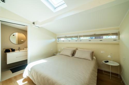 a bedroom with a white bed and a mirror at Relais Lungolago Gavirate in Gavirate