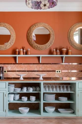 a kitchen with orange walls and white dishes on shelves at Hotel Boutique Casa Treviño in Campo de Criptana