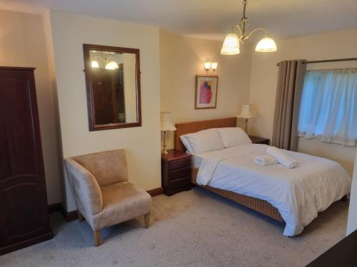 a bedroom with a bed and a chair and a mirror at Maryland Cottage Nr Gatwick in Godstone