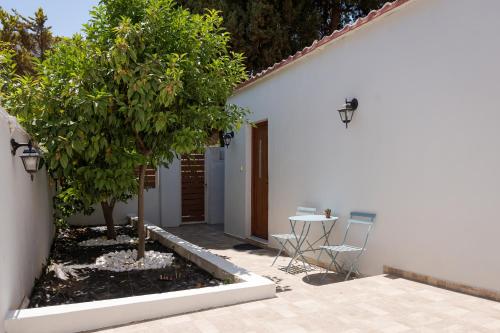 a white house with a table and a tree at Utopia Suites in Egina