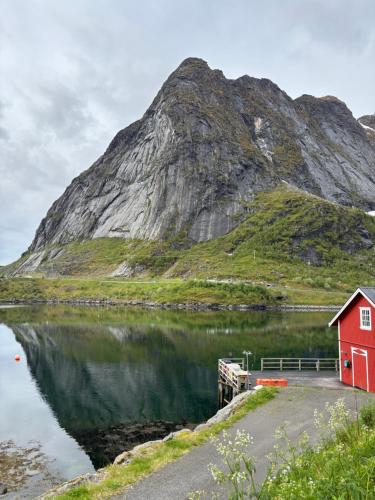 a red house next to a body of water with a mountain at Lofoten Bed & Breakfast Reine - Rooms & Apartments in Reine