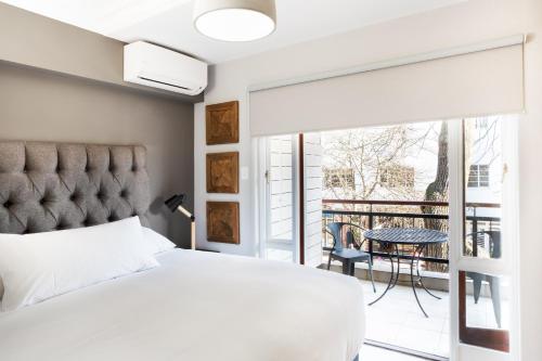 a bedroom with a bed and a balcony with a table at Avemore Jan Cats No 3 in Stellenbosch