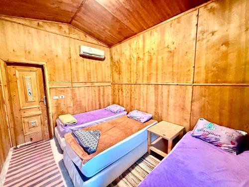 a room with two beds and a wooden wall at Moon Dune Camp in Nuweiba