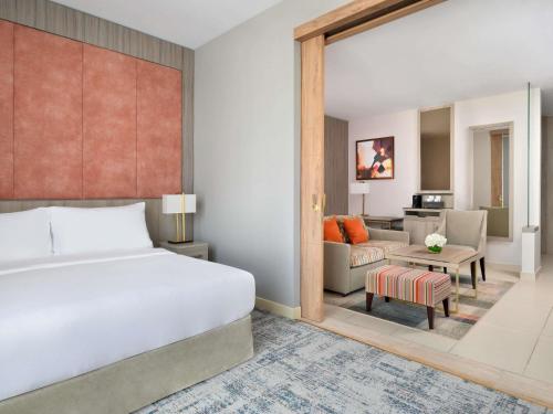 a bedroom with a bed and a living room at Mövenpick Hotel Tahlia Jeddah in Jeddah