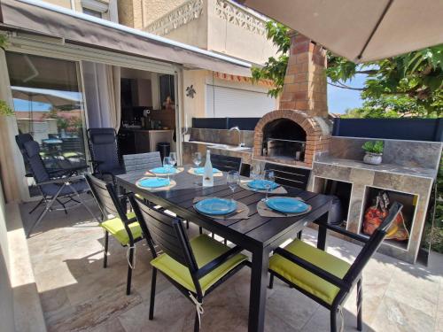 a patio with a table and chairs and a fireplace at Nouveau ! Maison Dora 4-6 pers à St Pierre La Mer proche de la plage et de toutes commodités à pied in Saint Pierre La Mer
