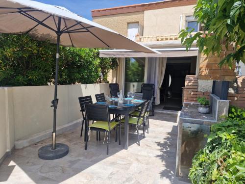 a table and chairs under an umbrella on a patio at Nouveau ! Maison Dora 4-6 pers à St Pierre La Mer proche de la plage et de toutes commodités à pied in Saint Pierre La Mer