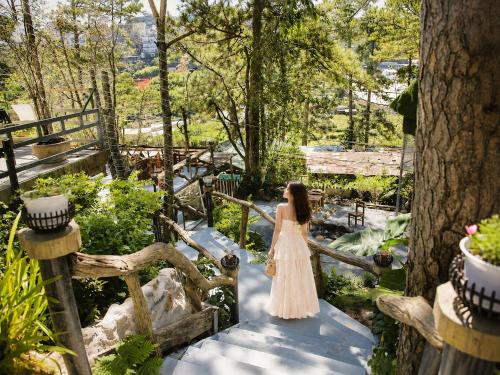 a woman in a dress walking down a wooden bridge at May Garden Home in Da Lat