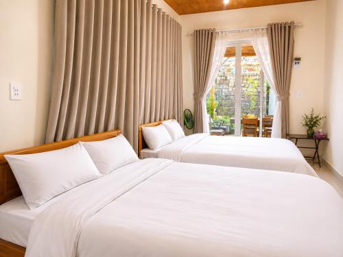 two beds in a room with a window at May Garden Home in Da Lat